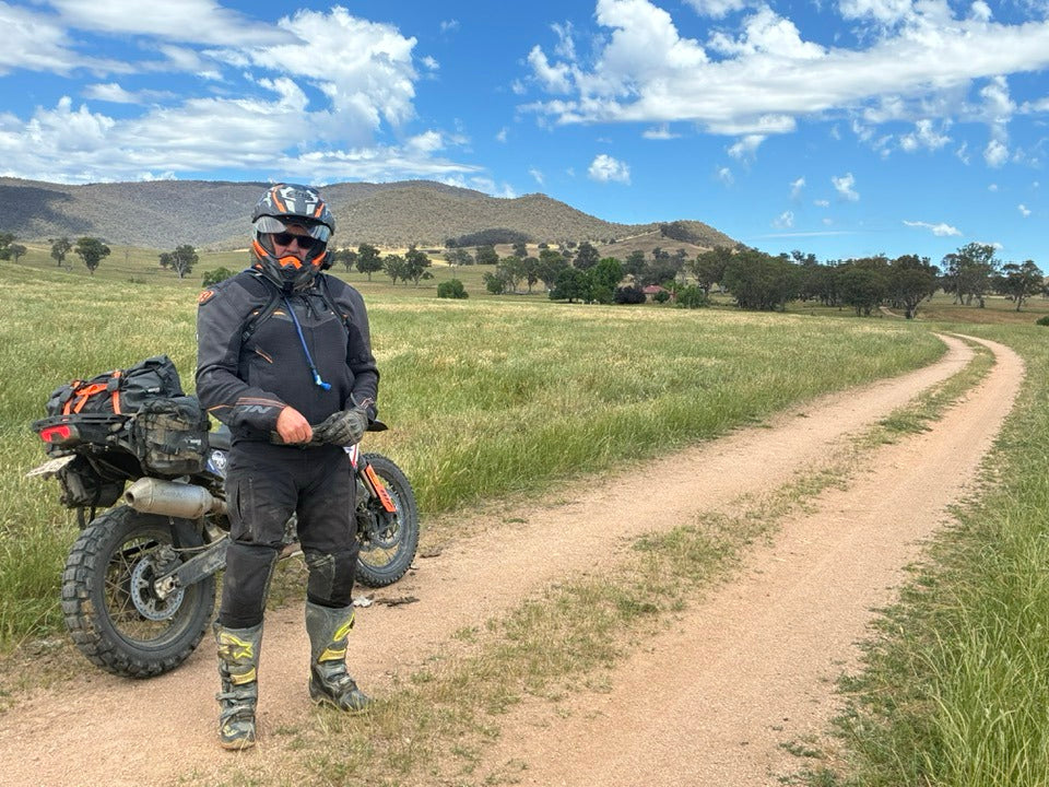 Person with a motorcycle on a dirt path in a scenic landscape